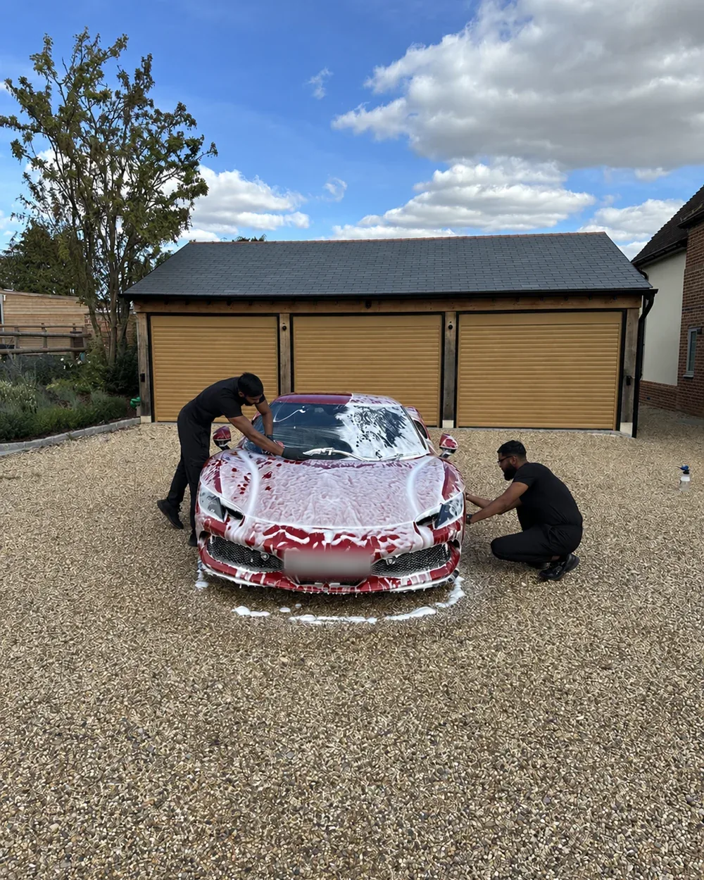 Both Mo's Valeting brothers washing a foam-covered Ferrari on a gravel driveway
