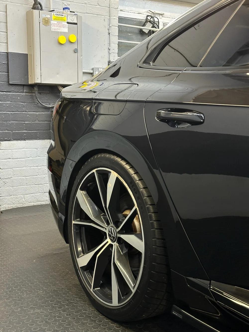 Two-stage paint correction in progress on a Volkswagen Arteon, the corrected panel reflecting the studio lights