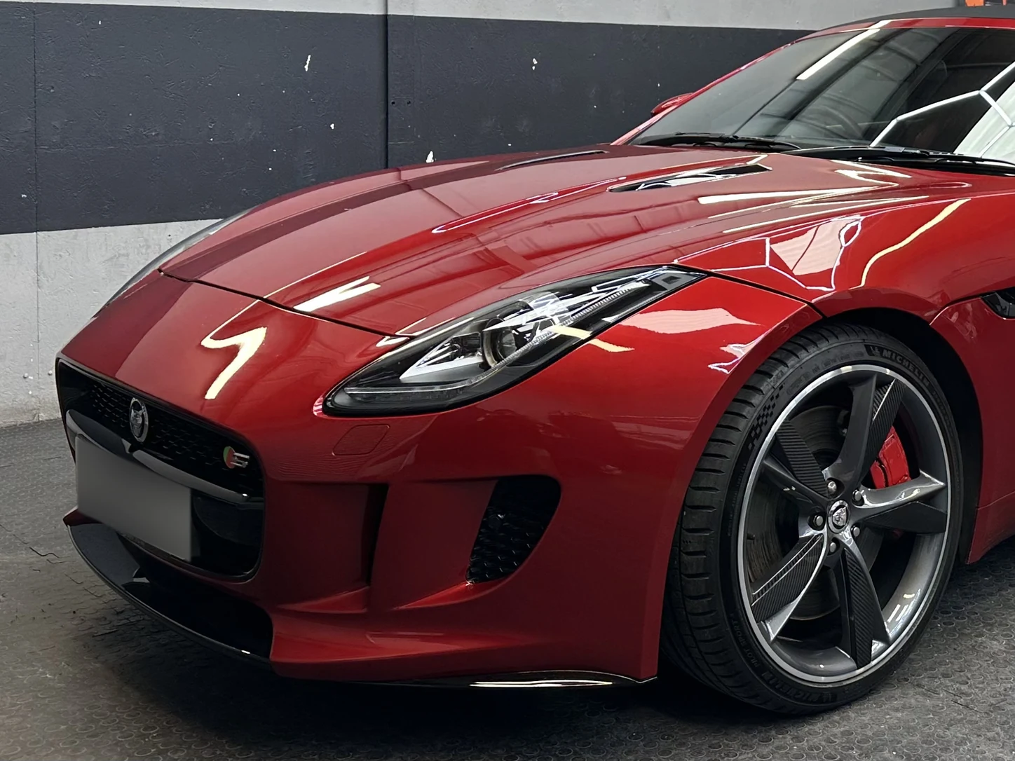 The front end of a red Jaguar F-Type with paint protection film fitted, the paint clear of chips
