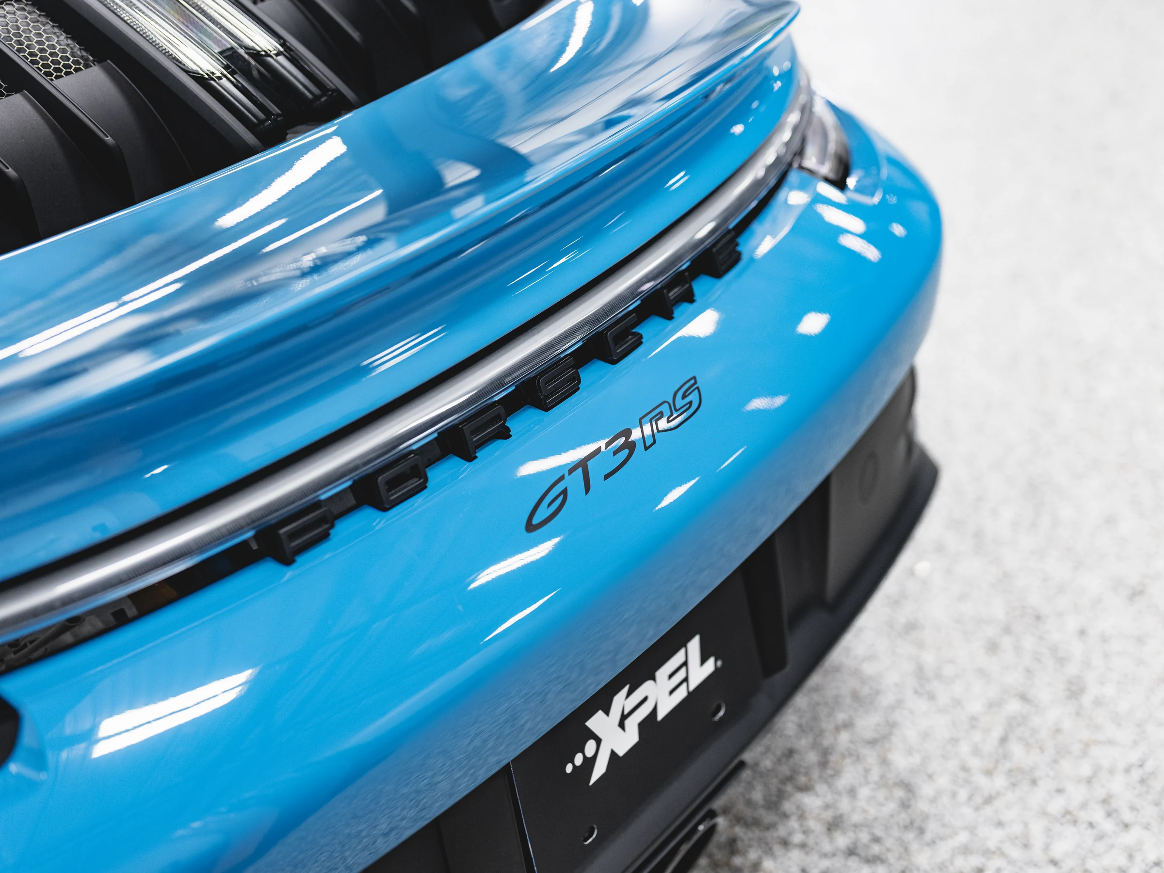 Close-up of the rear of a blue Porsche 911 GT3 RS with an XPEL plate, representing XPEL COLOR PPF