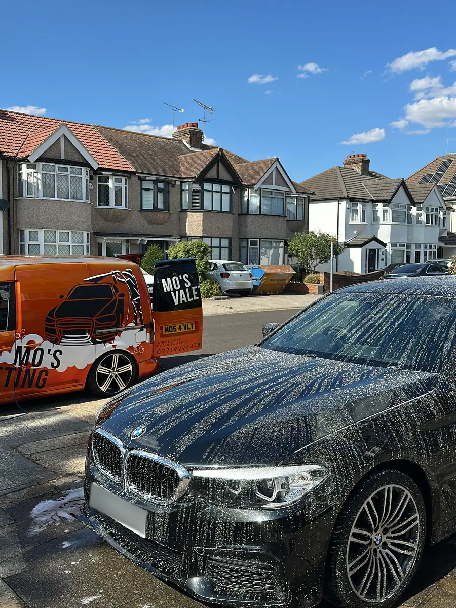A car being washed on a driveway with the Mo&rsquo;s Valeting van alongside