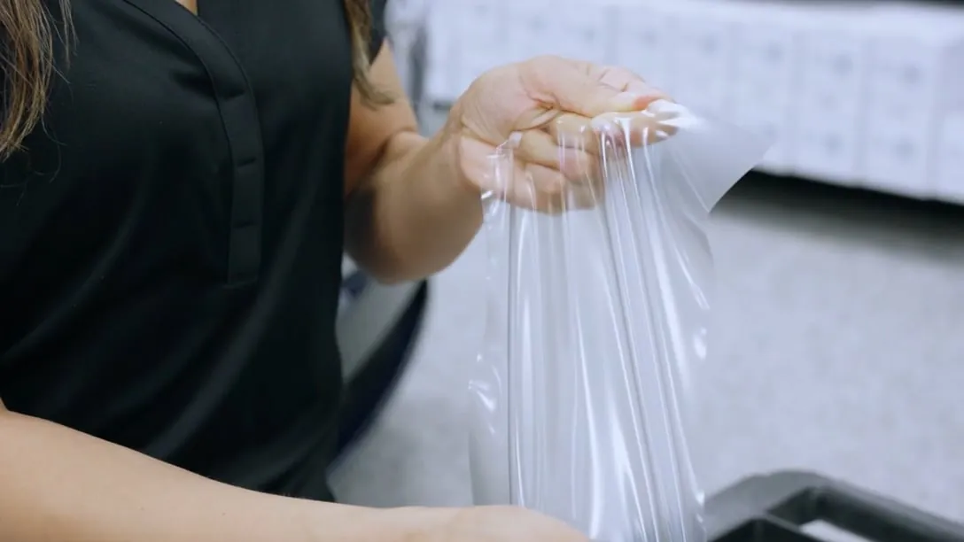 Two hands stretching a clear sheet of paint protection film